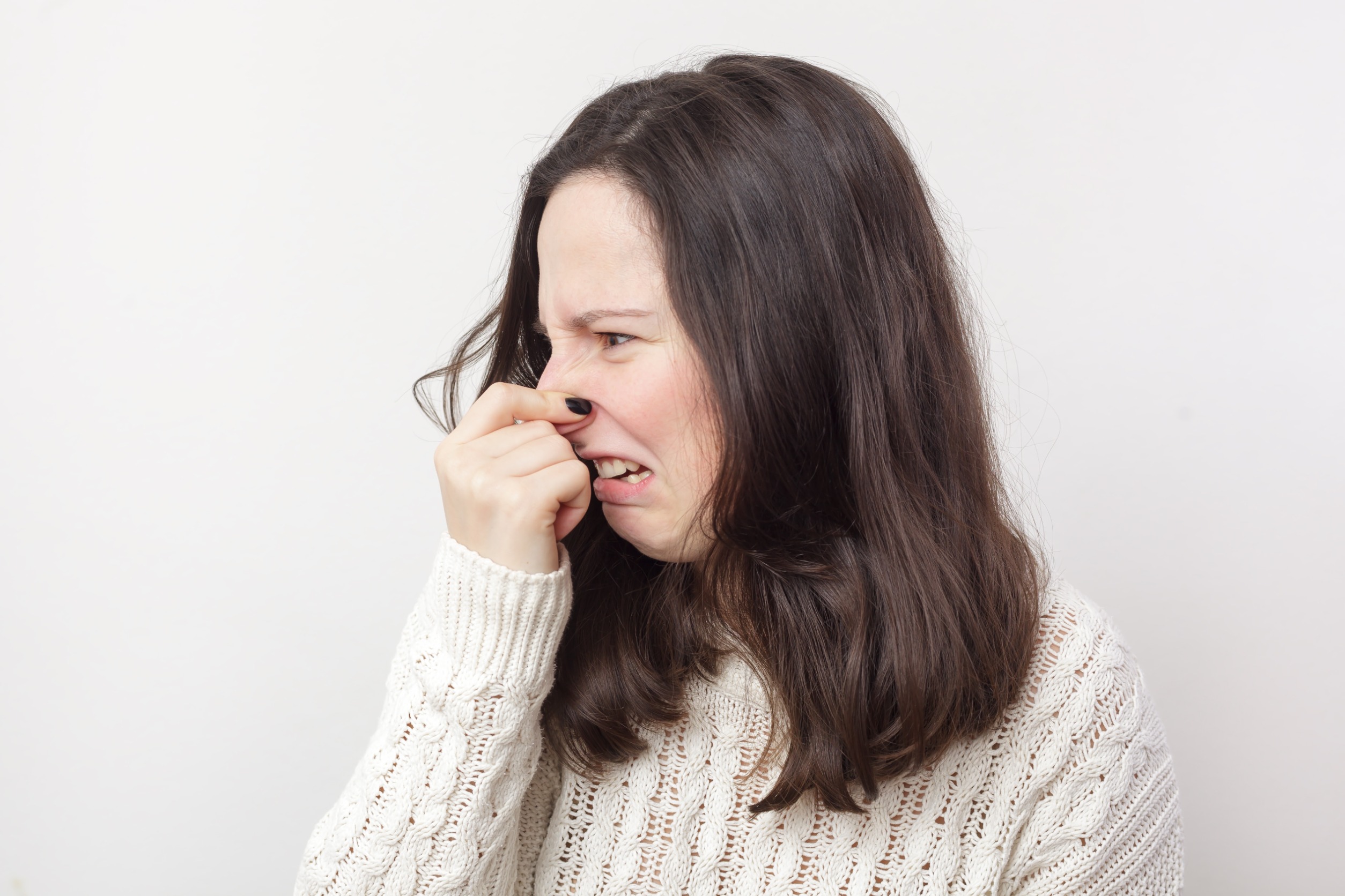 woman plugging nose due to smelly carpet